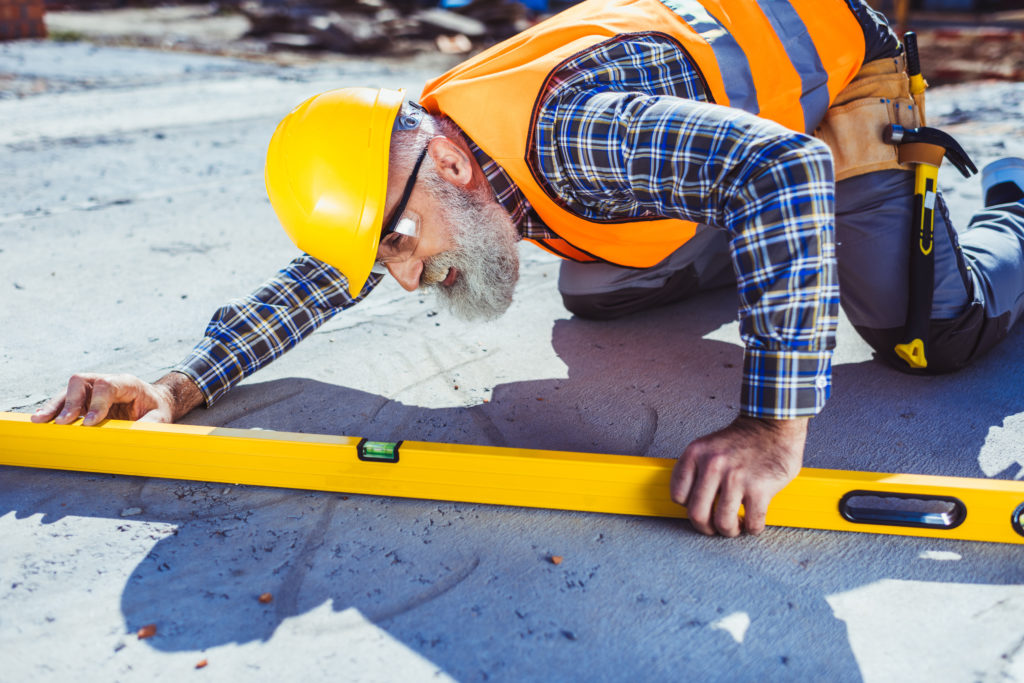 construction man looking at a level on the ground