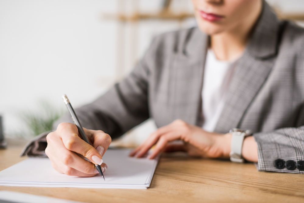 woman in grey suit jacket signing a graded death benefit life insurance policy