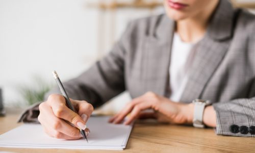 woman in grey suit jacket signing a graded death benefit life insurance policy